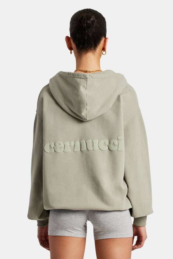 Female model wearing zip sage hoodie and showing back with cernucci logo