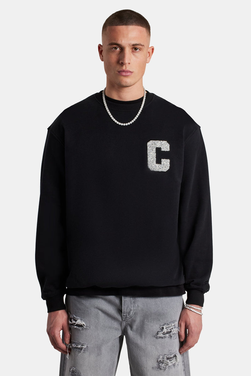 Male Model wearing black sweater with embellished C detail